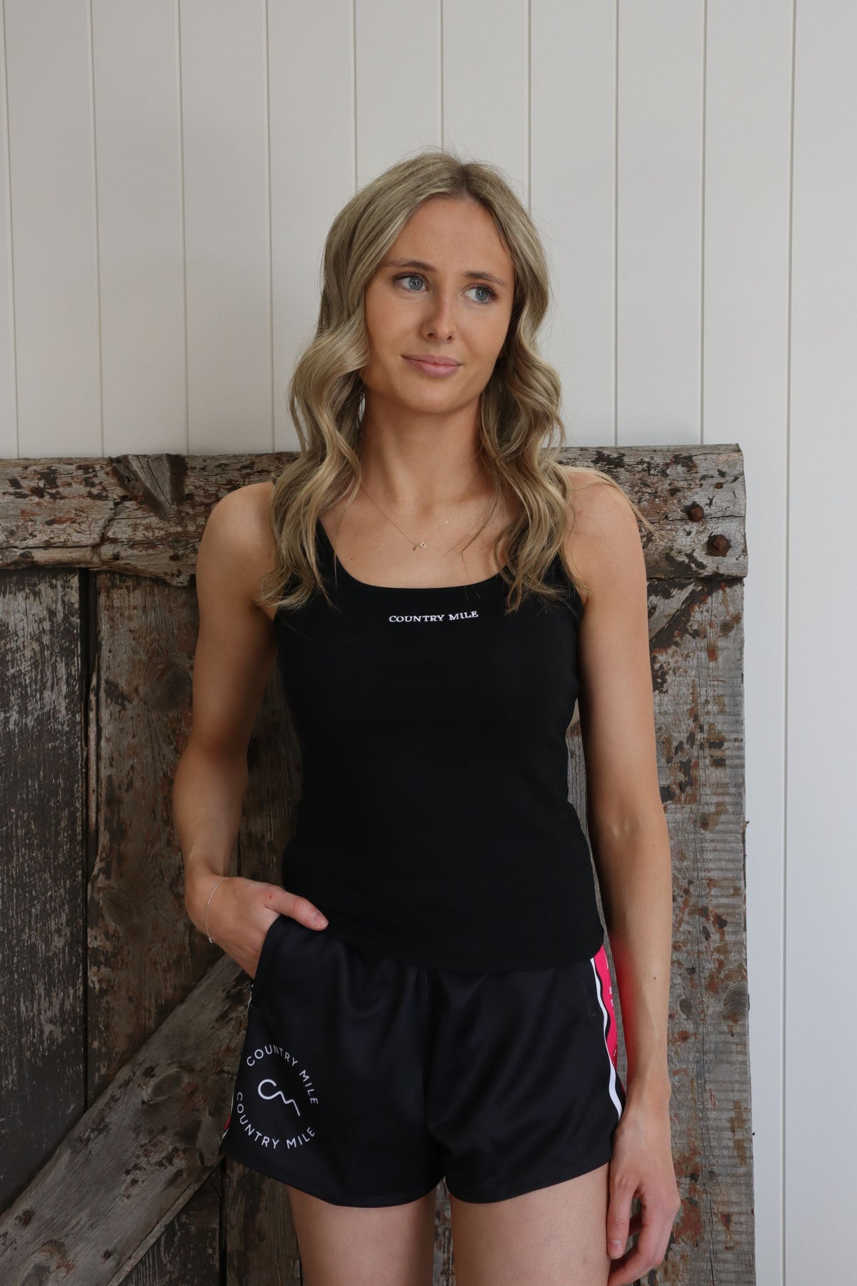 Model wearing Country Mile black and hot pink footy shorts with zip pockets and an adjustable waistband