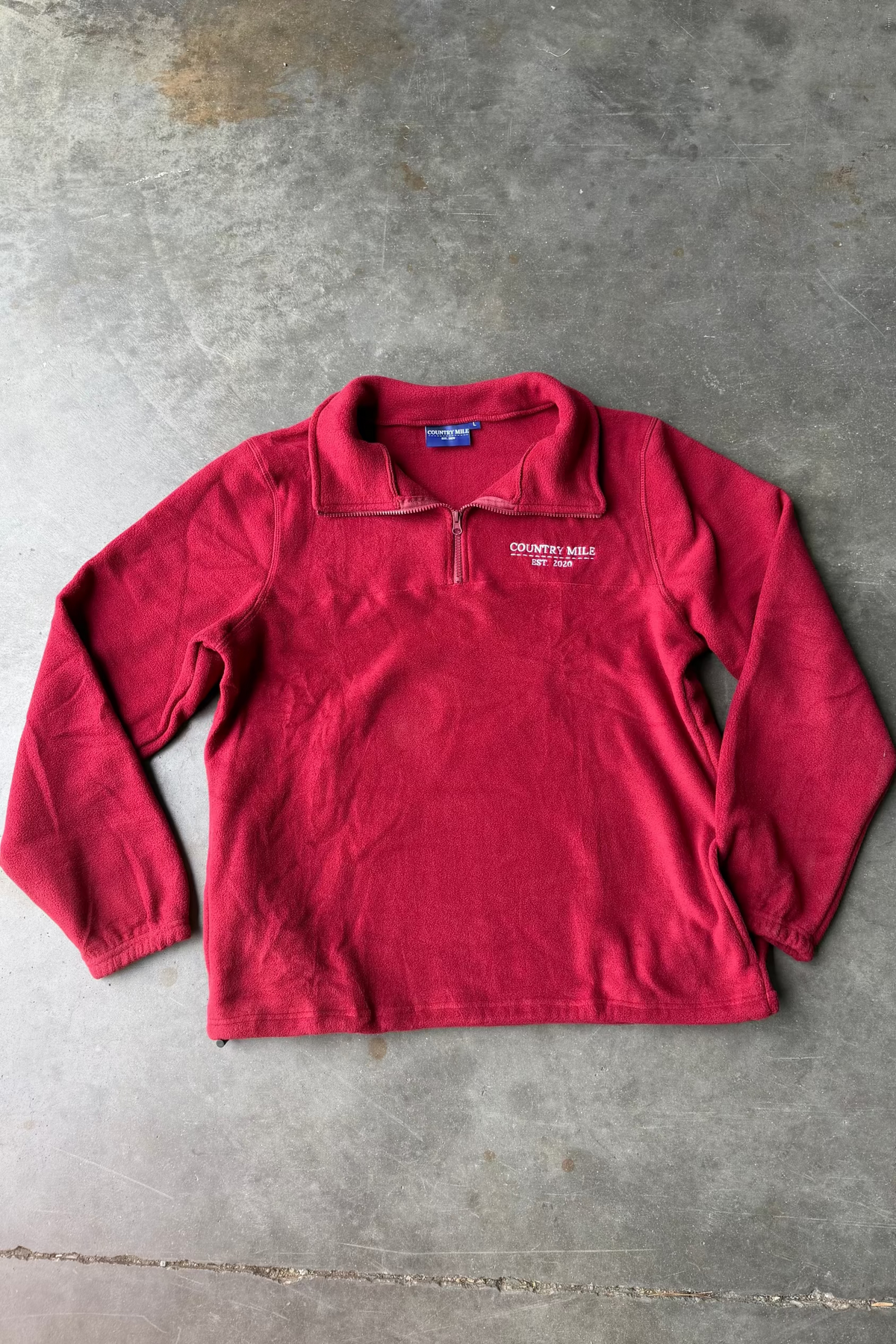 Red pullover with a brand logo on a concrete floor