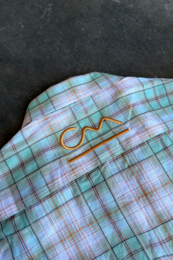 Close-up of the Chelsea Shirt in blue and teal plaid, showing the embroidered Country Mile logo on the chest
