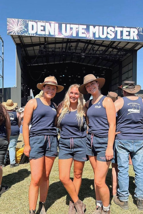 Three women wearing Country Mile Work Shorts and navy singlets at the Deni Ute Muster