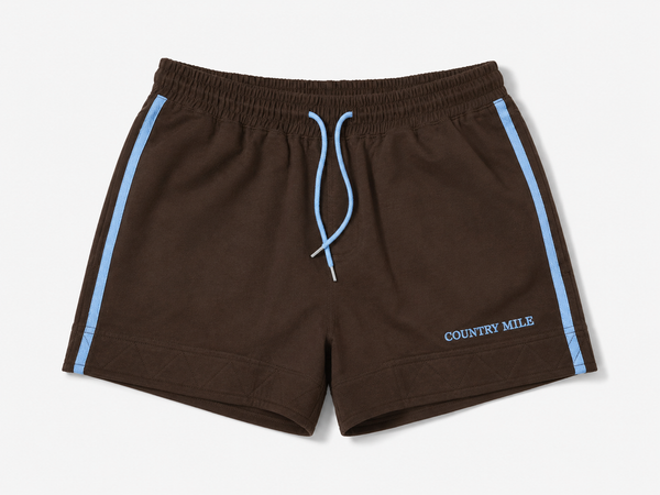 Dark brown work shorts with light blue side stripes, a matching light blue drawstring, and 'COUNTRY MILE' printed in light blue on the lower left leg, shown against a light gray background.