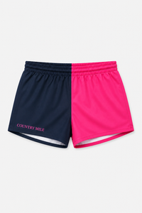 A pair of athletic shorts split vertically into two colors: navy blue on the left and bright pink on the right. The left leg features the text 'COUNTRY MILE' in pink.