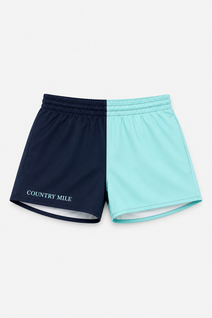 A pair of athletic shorts split vertically into two colors: navy blue on the left with 'COUNTRY MILE' printed in white, and light aqua/mint blue on the right, shown flat on a light gray background.