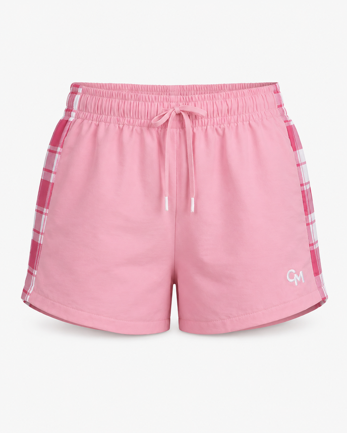 Pink athletic shorts with a white drawstring, white piping along the side seams, and a pink-and-white plaid pattern on the sides, featuring a small white 'CM' logo on the lower left leg.