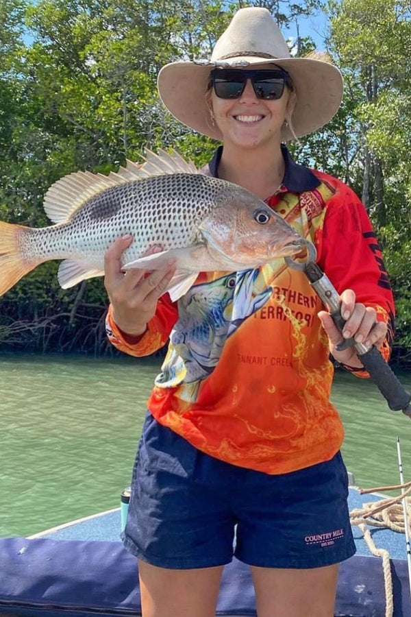 Woman wearing navy Country Mile Work Shorts while holding a fish on a boat